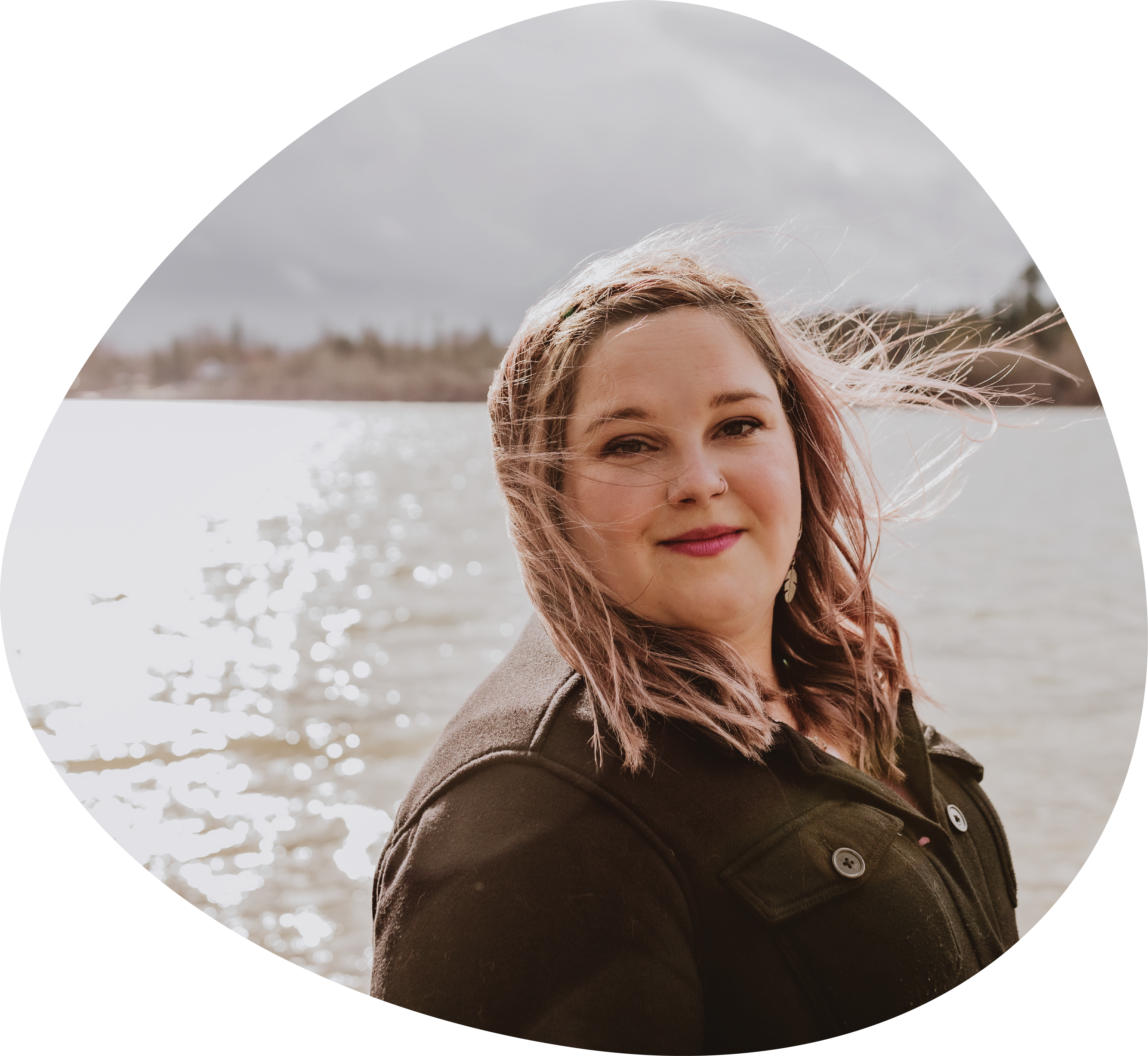 A photo of Marsha smiling in front of the Fraser River on a sunny day.