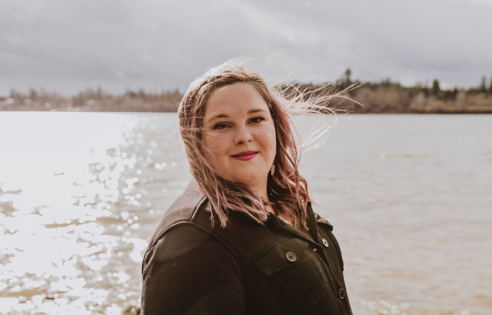 A picture of Marsha smiling at in the sun in front of the Fraser River, a place she loves